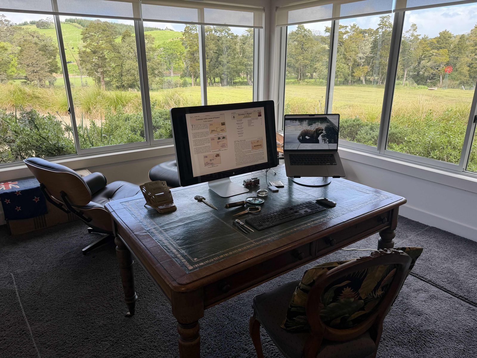 A leather-topped desk with a computer, magnifier and tongs, looking out over paddocks